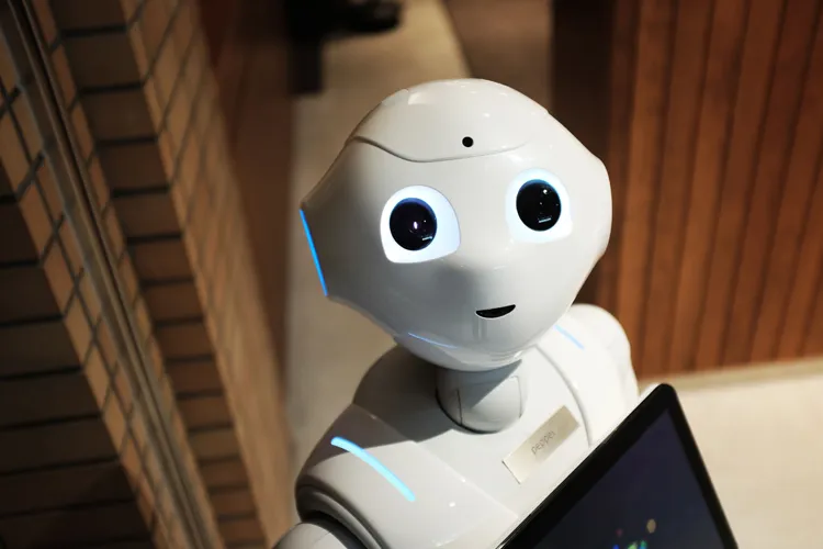 Een witte robot kijkt naar een scherm. Zo lees je de A.I-impact per studie.