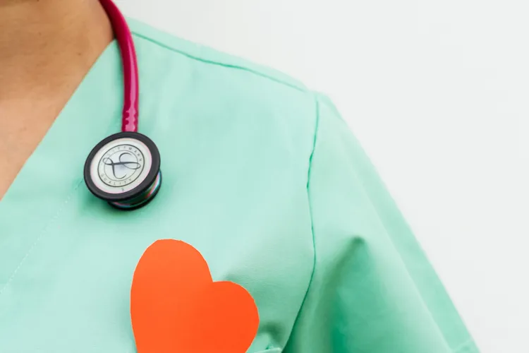 Zorgprofessional in groene scrubs met stethoscoop en een hart in de borstzak