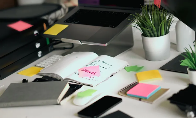 Bureau met laptop, notitieboek, planner en post-its om overzicht te houden tijdens je studie