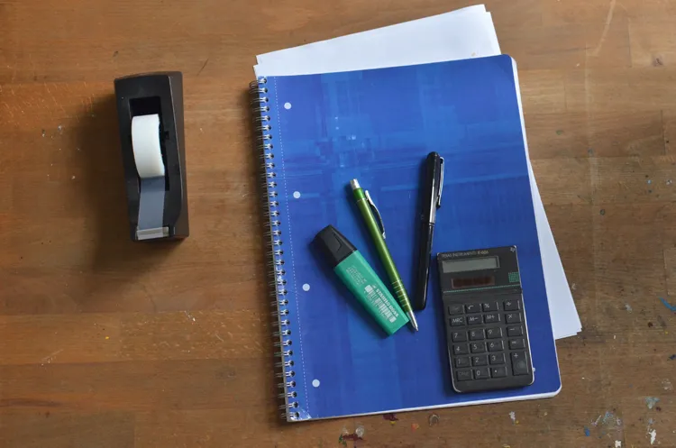 Studiebenodigdheden op een bureau: notitieboek, markeerstift, pen en rekenmachine voor een prettige studieomgeving