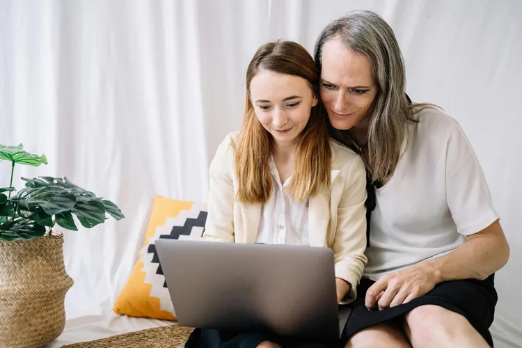 Ouder en dochter bekijken samen op een laptop tussenjaar programma's — gezamenlijke keuze tussen jongere en ouders